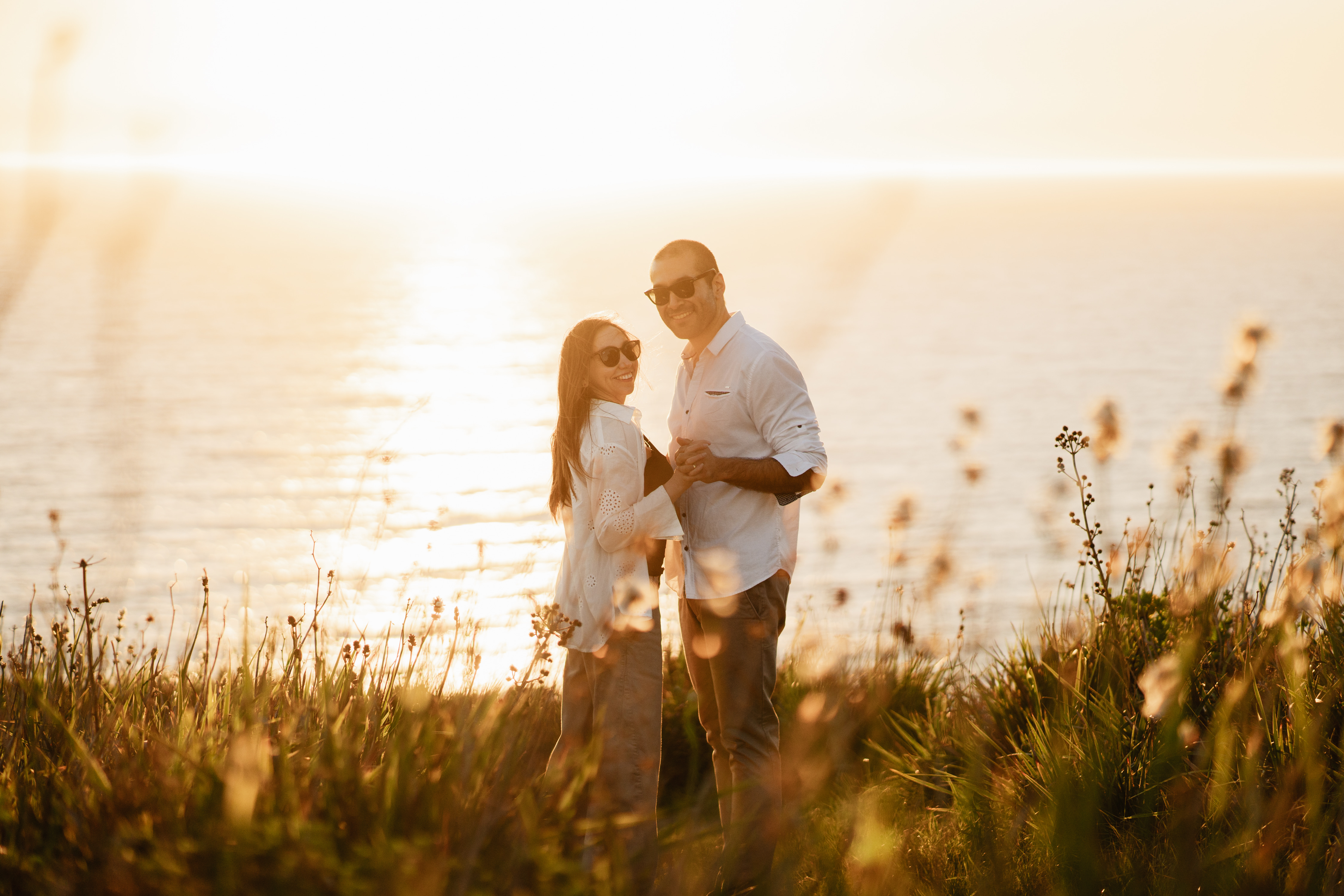 Evelyn y Rodrigo juntos frente al mar, iluminados por el atardecer